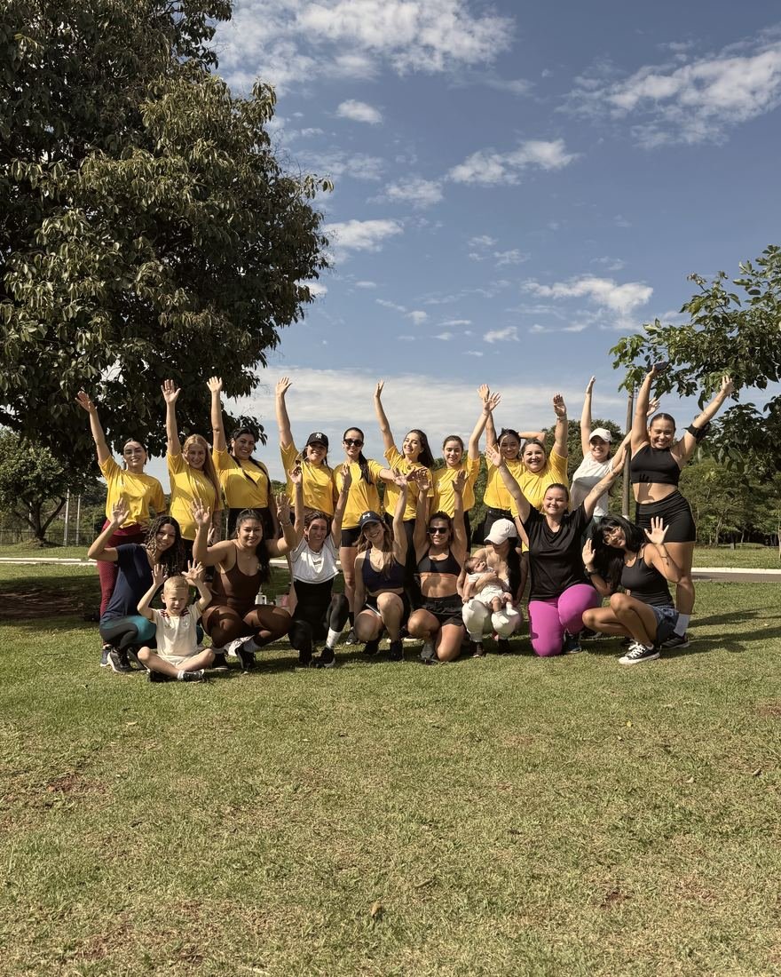 Grupo de mulheres reunidas em um parque com as mãos levantadas